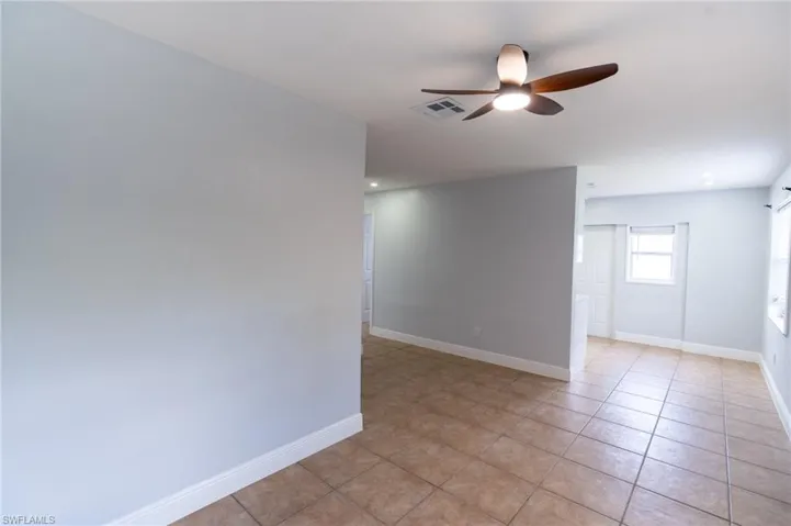 Tiled flooring extends throughout this interior space featuring a ceiling fan with integrated lighting, recessed lighting, and white baseboards