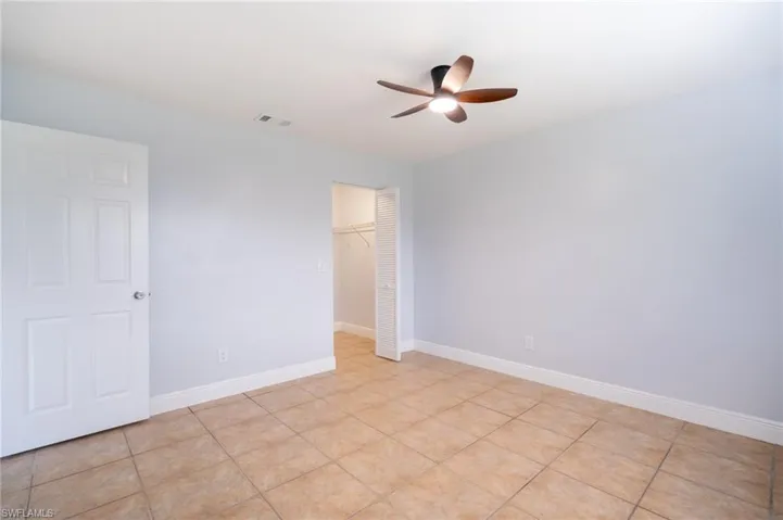 Neutral wall finishes with a ceiling fan, ceramic tile flooring, and a closet with bifold doors
