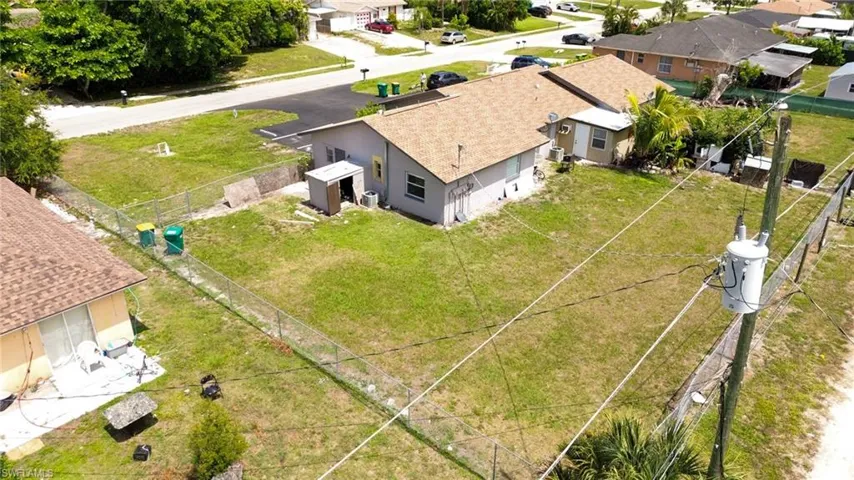 Expansive lot featuring a chain-link fence, mature trees, and a detached shed