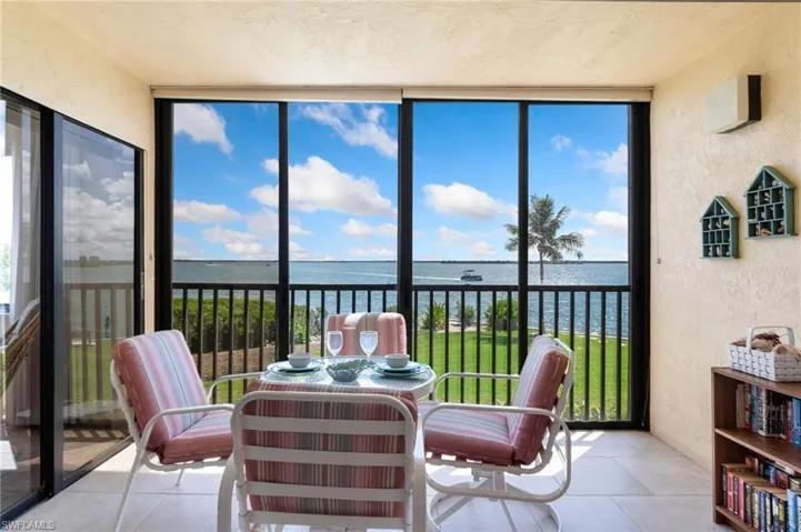 Sunroom featuring floor to ceiling windows, a textured wall, a water view, and tile patterned flooring