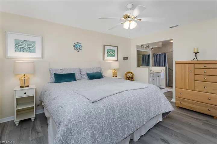 Bedroom with wood finished floors, a ceiling fan, and ensuite bath