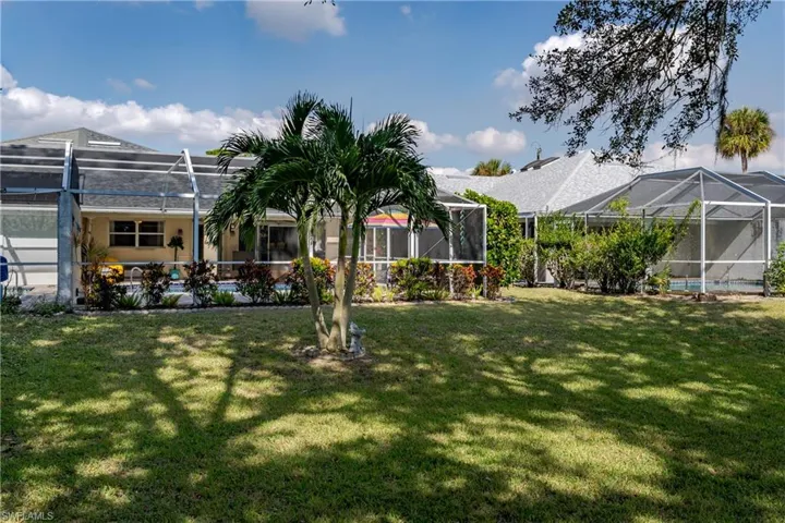 View of green lawn featuring a sunroom and glass enclosure