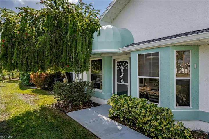 Property entrance featuring stucco siding and a lawn