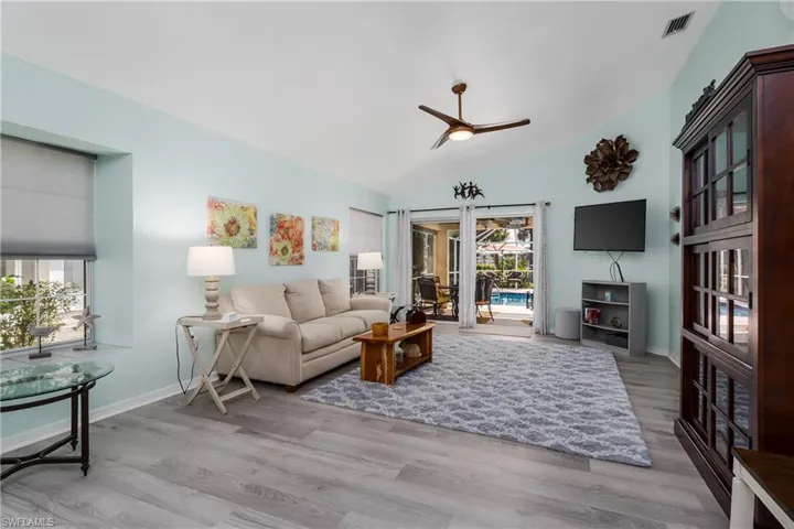Living room with light wood-type flooring, lofted ceiling, and ceiling fan