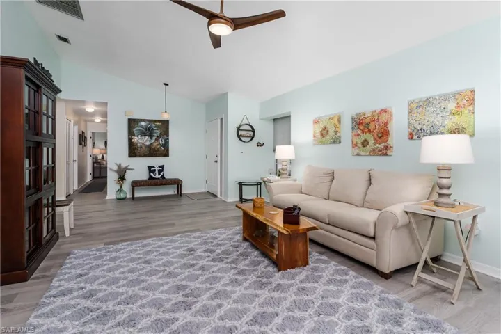 Living room with light wood-style floors, a ceiling fan, and lofted ceiling