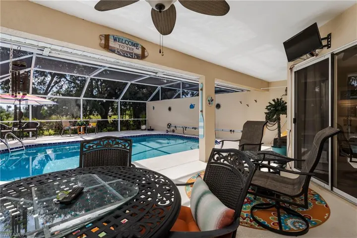 Outdoor pool featuring glass enclosure, a patio area, ceiling fan, and a sunroom