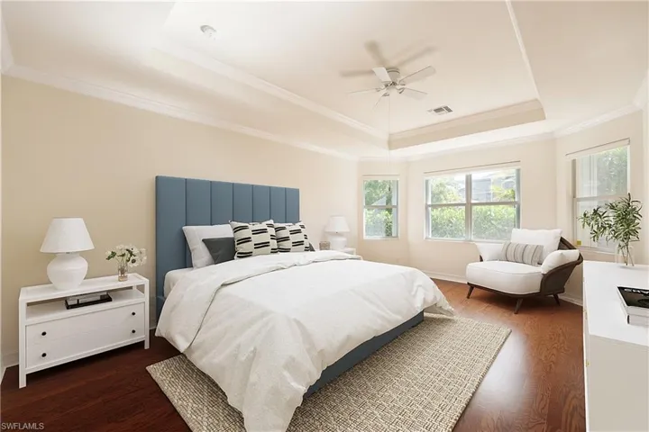 Bedroom with ceiling fan, dark wood-type flooring, a tray ceiling, and ornamental molding