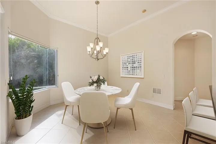 Tiled dining space with plenty of natural light, an inviting chandelier, and ornamental molding