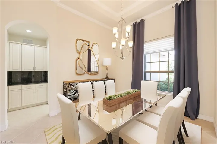 Dining space with an inviting chandelier, light tile patterned flooring, and ornamental molding