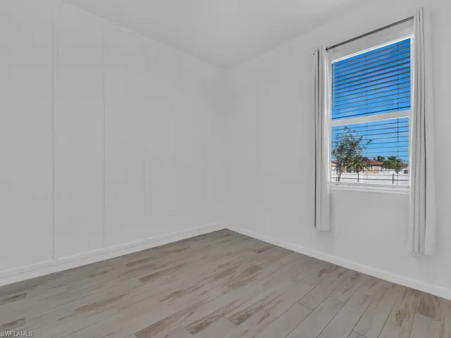 Empty room with light wood finished floors and a decorative wall