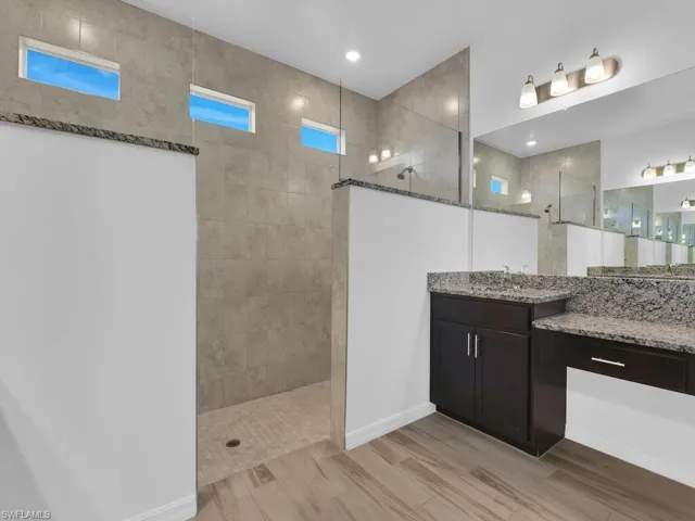 Bathroom featuring walk in shower, vanity, and light wood-type flooring