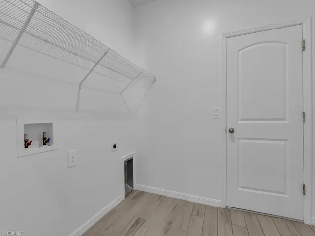 Laundry area with light wood-style flooring, hookup for a washing machine, and electric dryer hookup