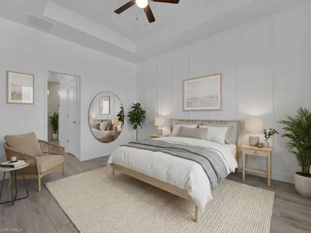 Bedroom featuring a raised ceiling, a decorative wall, light wood finished floors, and ceiling fan