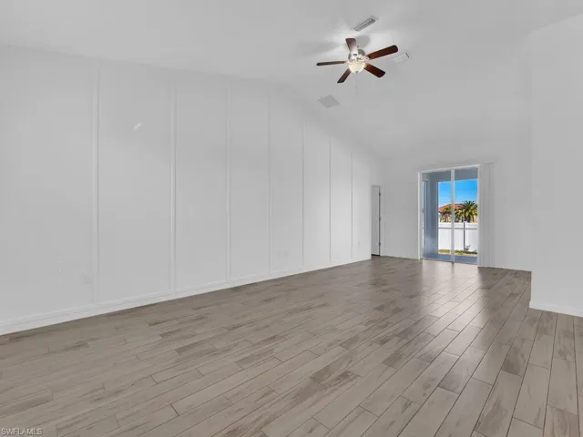 Unfurnished room featuring lofted ceiling, wood finished floors, and ceiling fan