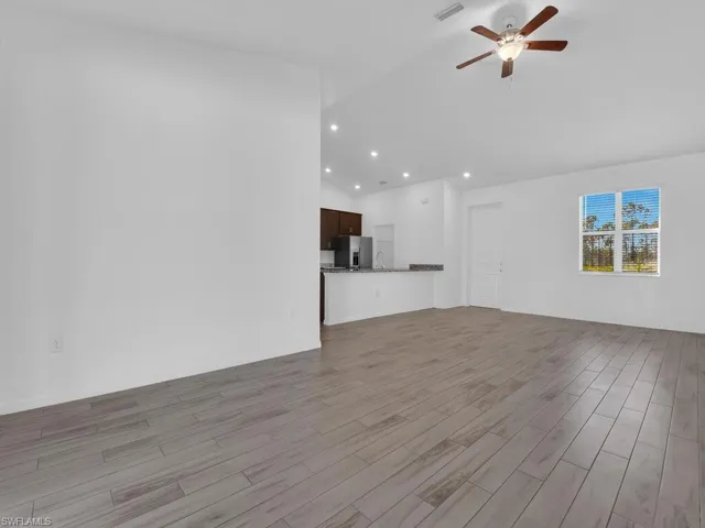 Unfurnished living room with lofted ceiling, dark wood-style flooring, a ceiling fan, and recessed lighting