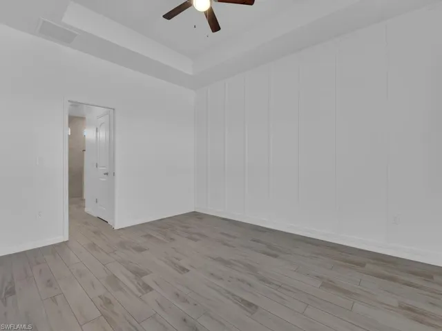 Spare room featuring a raised ceiling, light wood-style flooring, and ceiling fan