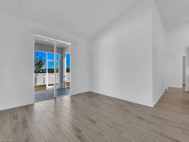 Empty room featuring light wood finished floors and vaulted ceiling