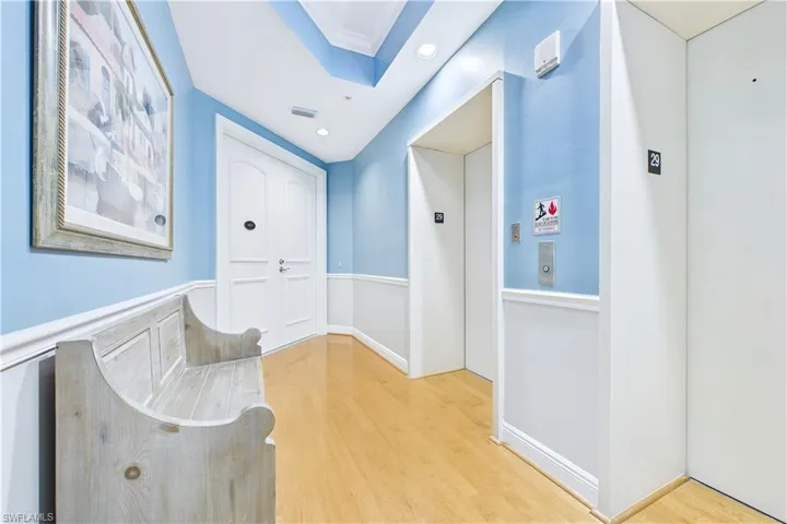 Hallway with elevator, light wood finished floors, crown molding, and recessed lighting