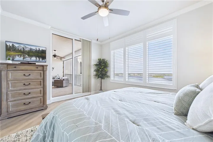 Bedroom featuring ornamental molding, light wood-type flooring, a ceiling fan, and access to exterior