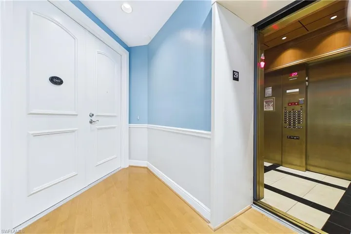 Doorway with elevator and wood finished floors