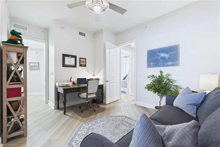 Home office with light wood-style flooring and ceiling fan