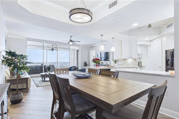 Dining area featuring a tray ceiling, ornamental molding, light wood finished floors, a ceiling fan, and recessed lighting