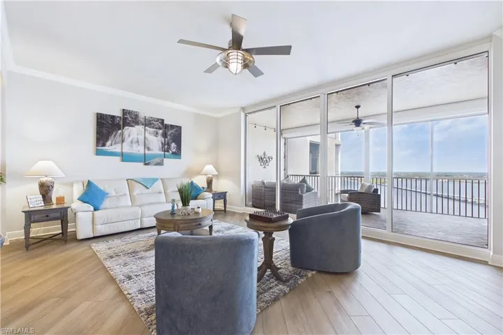 Living room with ceiling fan, ornamental molding, floor to ceiling windows, and light wood-style flooring