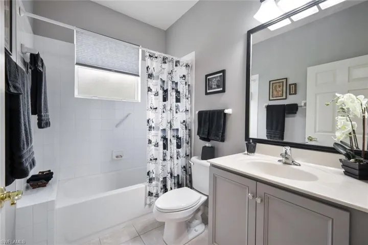 Full bathroom featuring tile patterned flooring, vanity, toilet, and shower / tub combo with curtain
