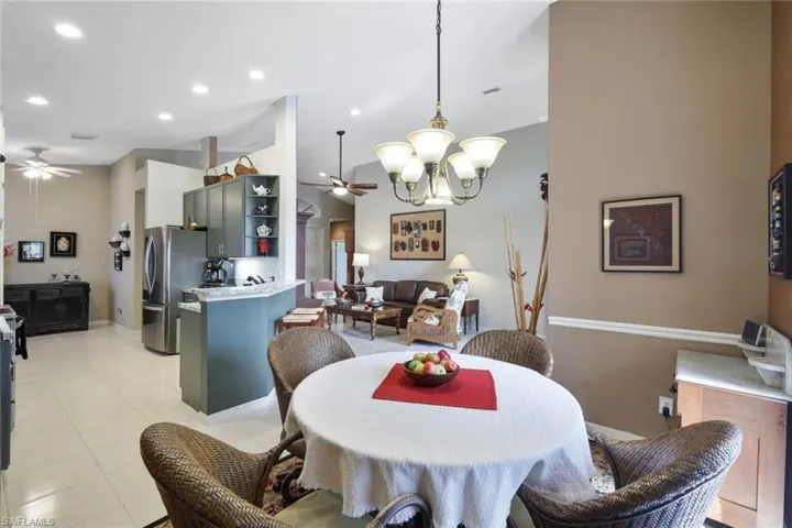 Dining space with ceiling fan with notable chandelier and light tile patterned floors