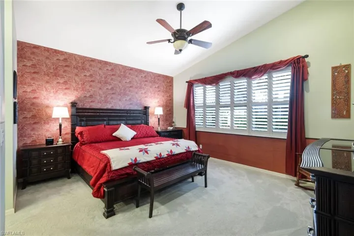 Bedroom featuring light carpet, vaulted ceiling, and ceiling fan