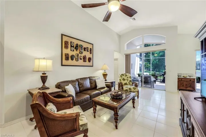 Living room featuring ceiling fan, light tile patterned floors, and vaulted ceiling