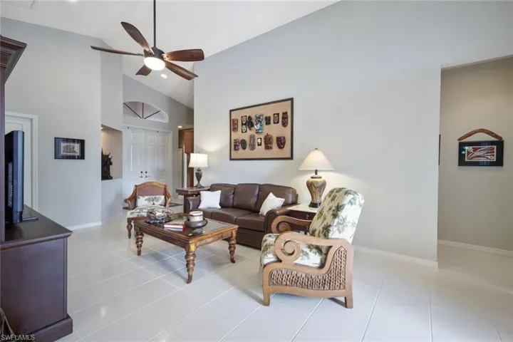 Tiled living room with ceiling fan and high vaulted ceiling