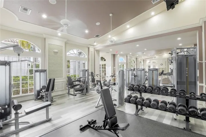 Gym with ornamental molding, vaulted ceiling, and ceiling fan