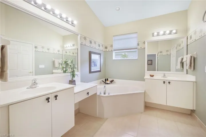 Bathroom featuring vanity, vaulted ceiling, a bathing tub, and tile patterned floors