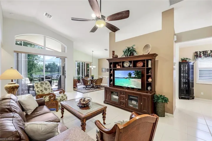 Tiled living room featuring lofted ceiling, a healthy amount of sunlight, and ceiling fan