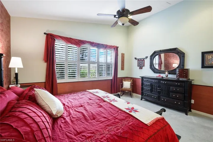 Carpeted bedroom featuring ceiling fan and vaulted ceiling