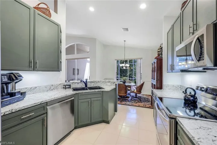 Kitchen with plenty of natural light, green cabinetry, sink, and appliances with stainless steel finishes