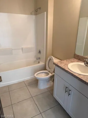 Bathroom featuring vanity, shower / washtub combination, and light tile patterned flooring