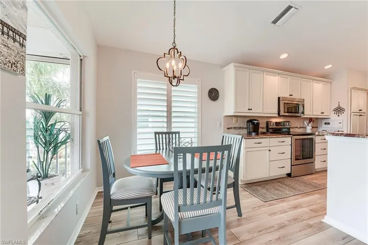 Dining space with a wealth of natural light, visible vents, a notable chandelier, and light wood-type flooring