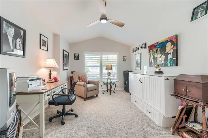 Office area featuring baseboards, lofted ceiling, light colored carpet, and ceiling fan