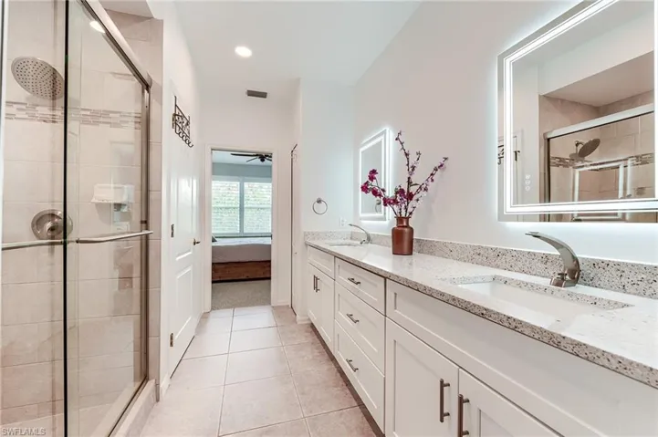 Bathroom featuring double vanity, a sink, tile patterned floors, and a shower stall