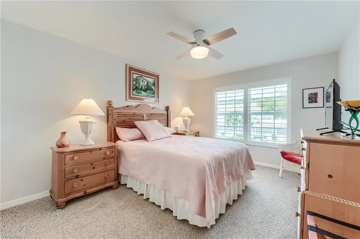 Bedroom featuring a ceiling fan, baseboards, and light colored carpet