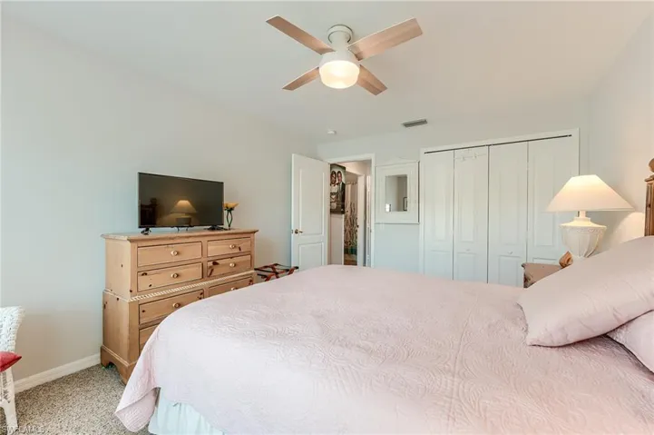 Carpeted bedroom with baseboards, visible vents, a closet, and a ceiling fan