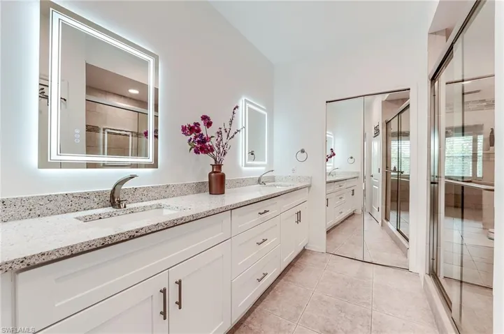 Full bathroom featuring double vanity, a sink, and a shower stall