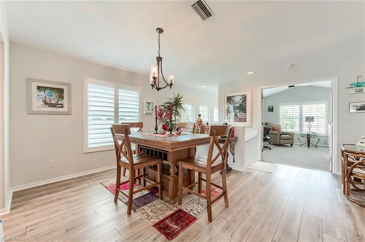 Dining area featuring a notable chandelier, baseboards, light wood finished floors, and visible vents
