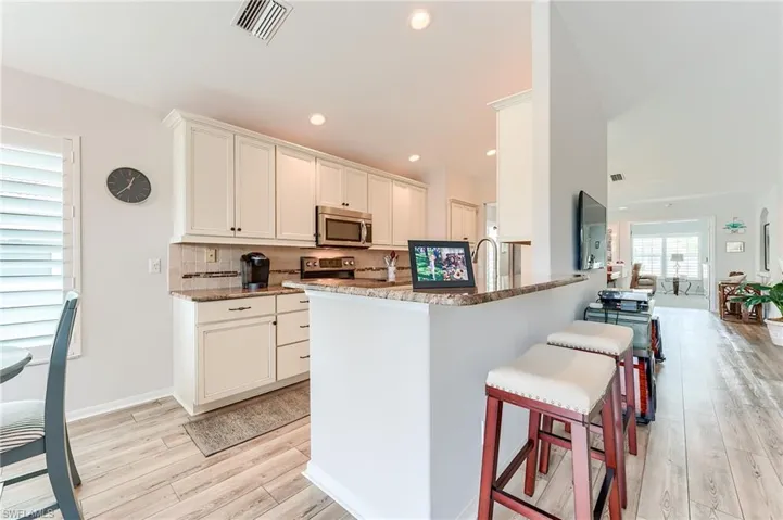 Kitchen featuring tasteful backsplash, a breakfast bar area, stainless steel appliances, visible vents, and light wood-style flooring