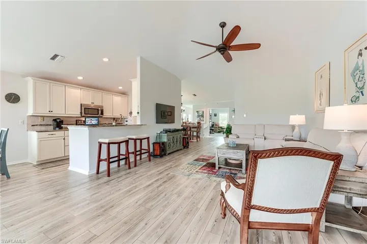 Living area with light wood-type flooring, recessed lighting, visible vents, and ceiling fan
