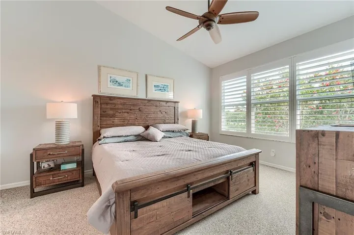 Bedroom featuring a ceiling fan, light carpet, baseboards, and lofted ceiling