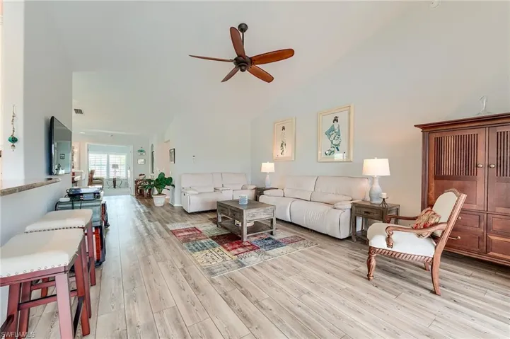 Living area featuring high vaulted ceiling, light wood-style floors, and ceiling fan