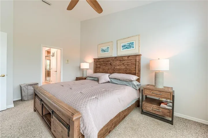 Bedroom with baseboards, ensuite bath, visible vents, and light colored carpet